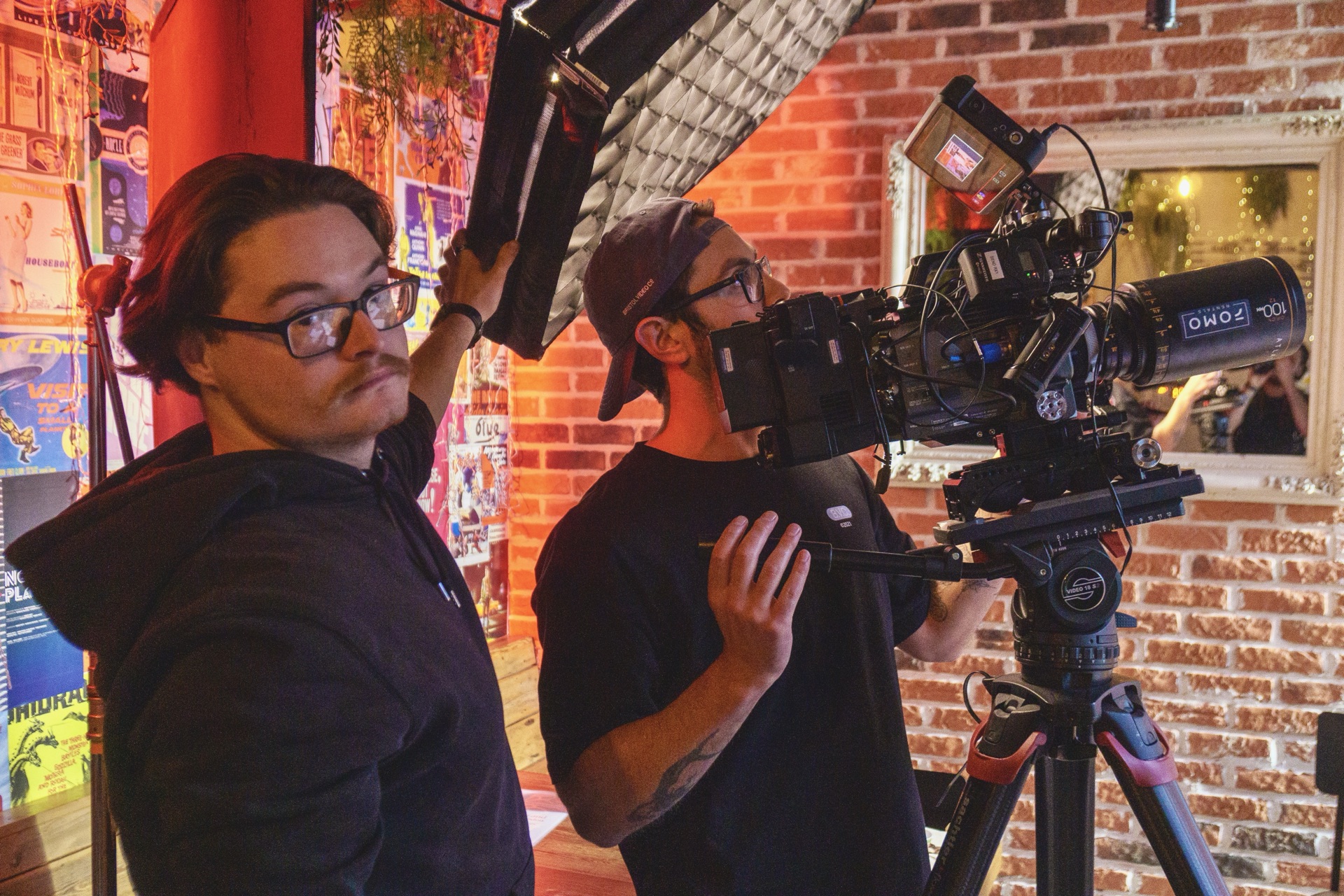 Bristol Video Company crew filming on set, camera with cinema lens on a tripod and softbox lighting against an exposed brick wall